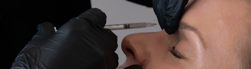 Woman receiving neuromodulator injection for frown lines at the symm label in Calgary