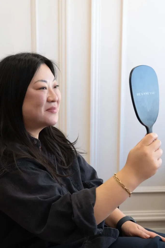 patient looking in the mirror after masseter botox treatment at the symm label in Calgary